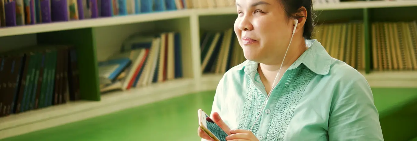 Mulher com camisa verde segurando um smartphone que lê a tela do Portal de Acessibilidade da MRV